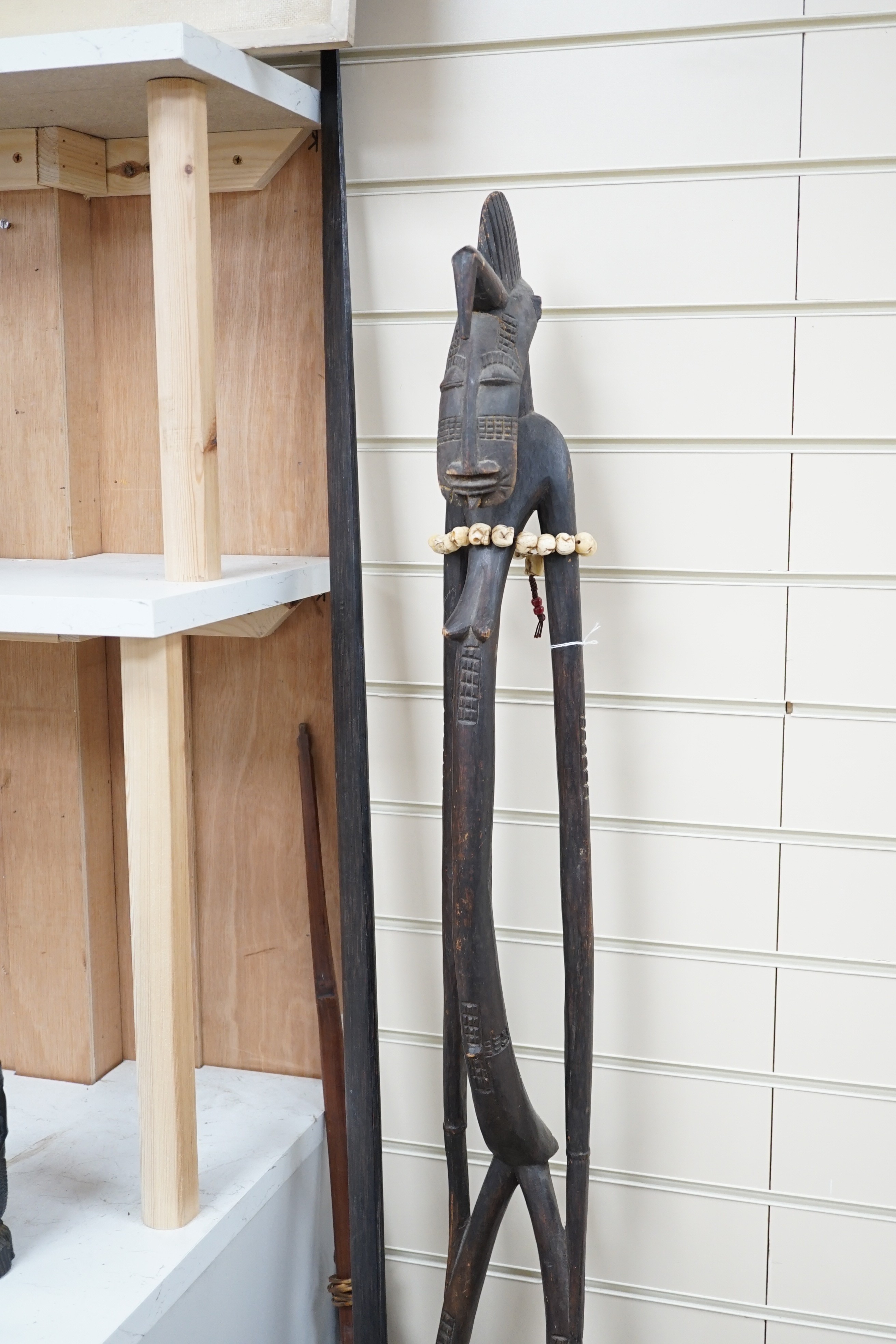 Four tribal hardwood carvings, two bows and two bronze spears longest 85cm